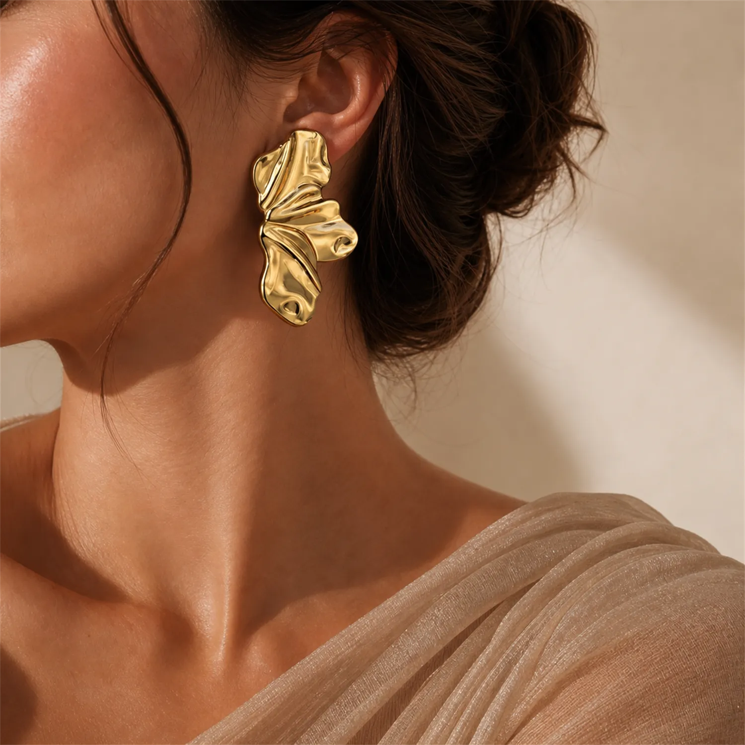 Gold-toned statement earrings styled with a neutral outfit